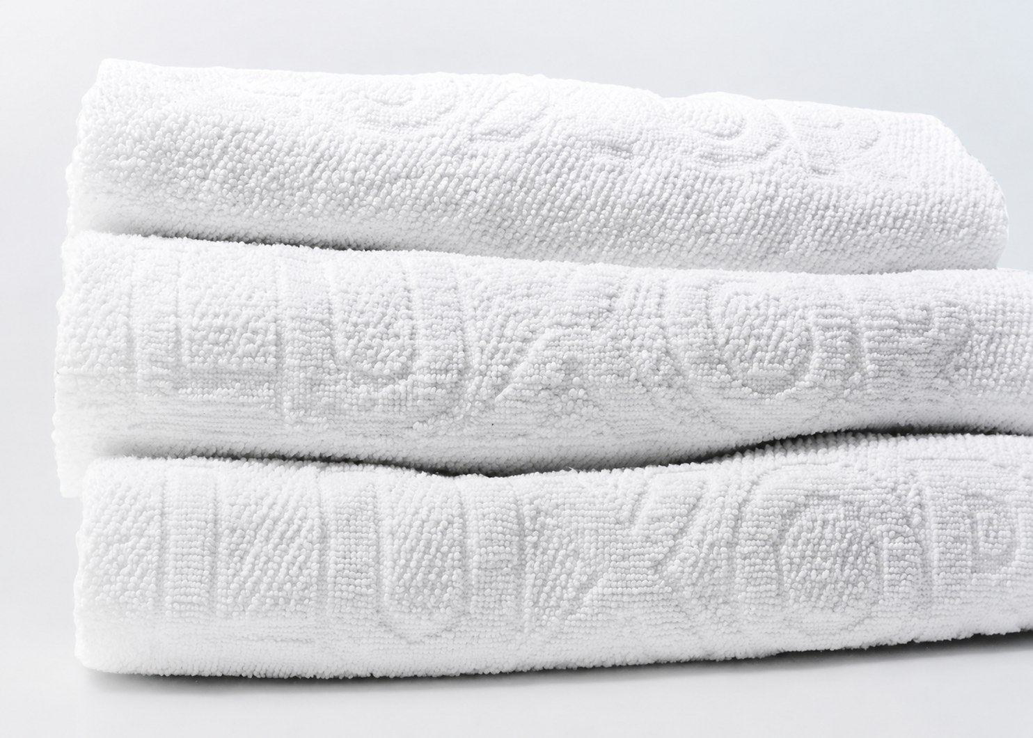 Toalhas Luxor dobradas, textura macia com relevo da marca
